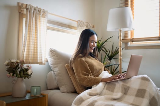 Relaxed young woman browsing the internet on her laptop at home.