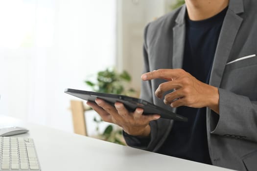 Professional businessman reviewing financial data on digital tablet at desk.