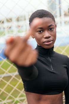 young african american female showing middle finger in town on summer day, selective focus on the face