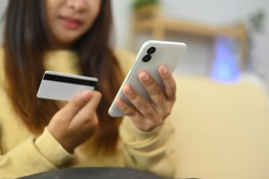 Cropped shot young woman shopping online with smartphone and credit card.