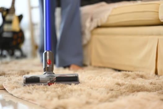 Close up of woman vacuuming a fluffy rug in a cozy home.