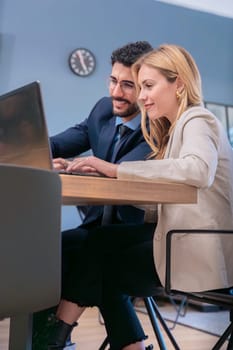 Two business colleagues collaborate in a modern office, smiling as they work together on a laptop. They share ideas in a professional yet friendly environment, fostering productivity and teamwork.