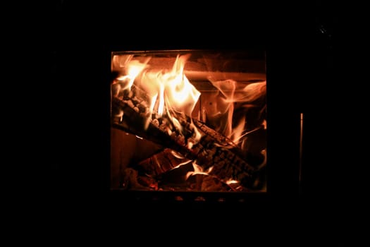 Bright colored dancing flames in fireplace. Close up of burning firewood. Cozy warm background.