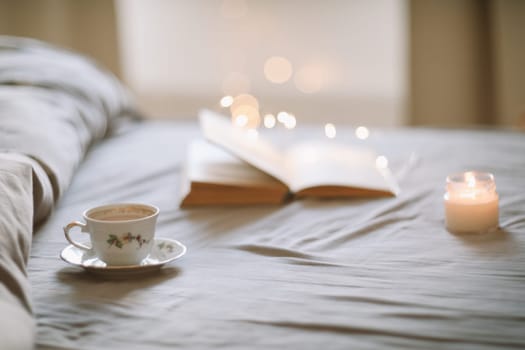 A cup of coffee and a book lying on the bed in a white bedroom. High quality photo