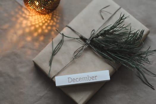 Christmas composition. Gift, fir tree branches, balls on craft paper background. Christmas, winter, new year concept. Flat lay, top view, copy space.