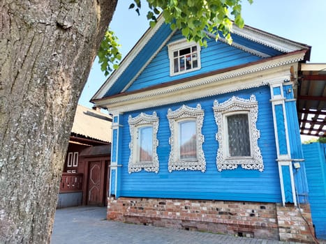 A colorful wooden house features intricate window designs in a quaint village.