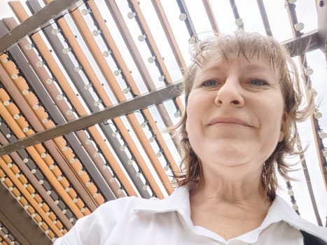 A woman captures her excitement while touring a unique, contemporary building during her travels. The adventures of middle-aged female tourist on a trip