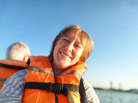 A tourist enjoys taking selfies on a boat while wearing a life jacket, capturing the joyful moment on a sunny day by the water