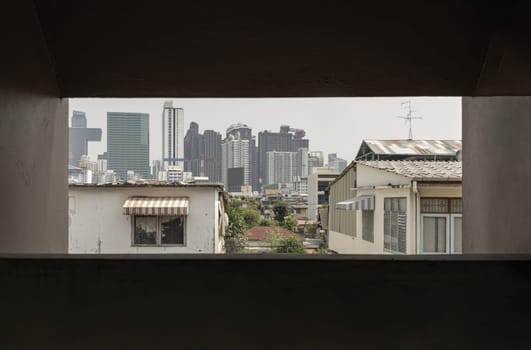 Bangkok, Thailand - 27 Feb 2023 - Cityscape view of Bangkok with a mix of Old house and Modern skyscrapers background. Architectural View of Old and New Buildings in Contrasting Classical and Modern Designs, Look through the window frame in Old building, Space for text, Selective Focus.