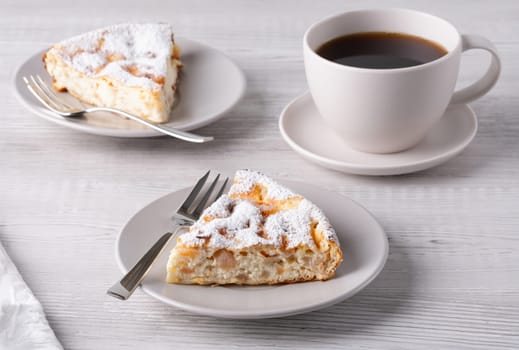 Two delicious pieces of cottage cheese casserole and coffee on a light wooden table.