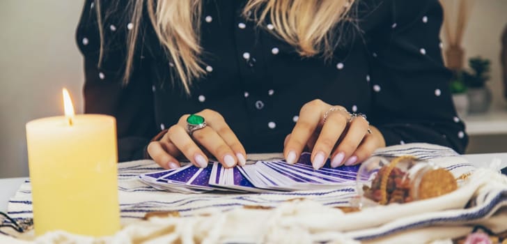 A fortune teller reads with tarot cards. Selective focus. Woman.