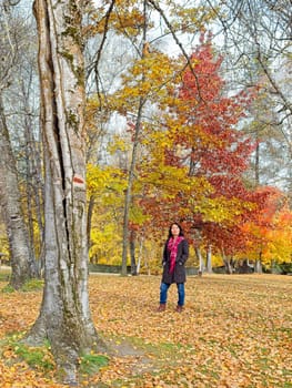 A woman in a stylish coat and a red scarf strolls through a beautiful park in autumn in eastern Washington.