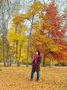 A woman in a stylish coat and a red scarf strolls through a beautiful park in autumn in eastern Washington.