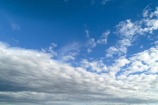 A calm and expansive blue sky filled with delicate white and gray clouds, creating a peaceful and open atmosphere.