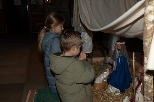 The children praying and looking at a Christmas nativity scene with baby Jesus Creche Figurines