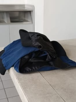 A casual blue and black jacket lies on a grey table, portraying simplicity and everyday fashion. Ideal for themes of casual style, fashion, and laundry.