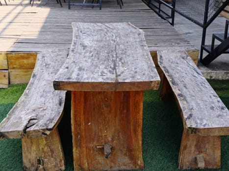 A rustic wooden table and benches set on an outdoor patio, showcasing natural, handcrafted design. Ideal for gatherings, creating a cozy and organic atmosphere.
