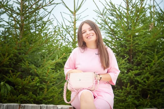 Portrait of young nice pretty woman with long brown hair in greenery