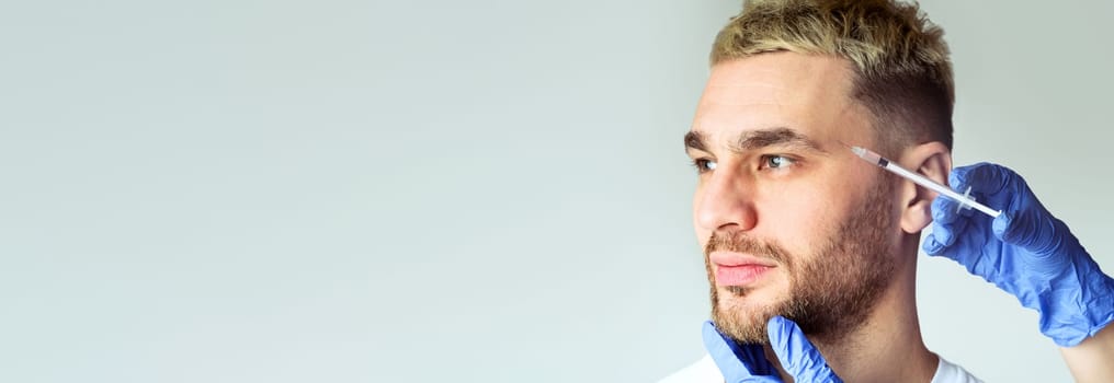 Male beauty care concept. Doctor makes beauty injection for man on gray background