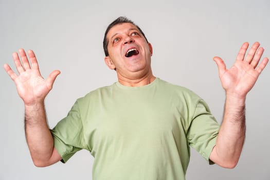 A middle-aged man with a neutral expression raises his hands in a questioning gesture against a plain backdrop close up