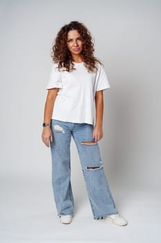 Woman with curly hair expresses confusion in a studio setting against a neutral background close up