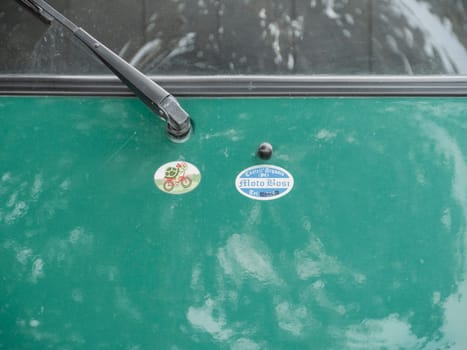Arquato, PC, italy - October 31st 2024 Close up view of a green car hood featuring a castel arquato per moto bosi sticker and a turtle riding a bicycle sticker, providing a glimpse into automotive personalization and branding