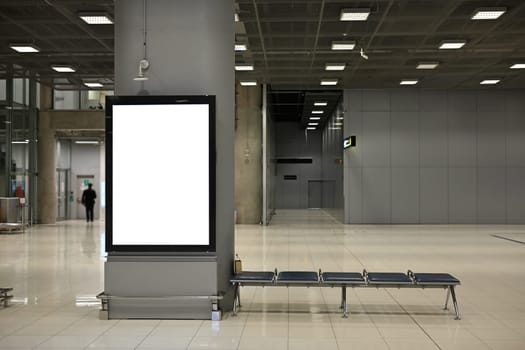 Spacious airport hall with empty seats and blank advertising screen.