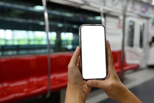 Hands holding a smartphone with blank screen in city subway.