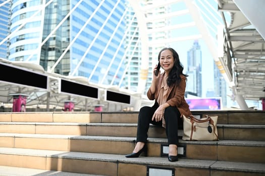 Confident mature businesswoman enjoying a phone conversation in modern city.