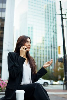 Young hispanic businesswoman talking on her cell phone while walking on city urban street.