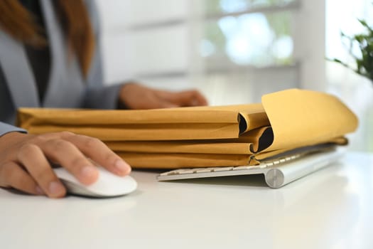 Cropped shot of businessperson organizing important documents in envelopes at office desk.
