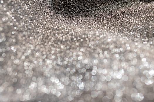 Silver glitter background material.Horizontal blurred metallic surface. Pure silver wire mesh. Wavy fabric with glitter. Used for backgrounds of fashion products
