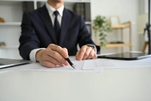 Professional businessperson reviewing contract documents at work desk.