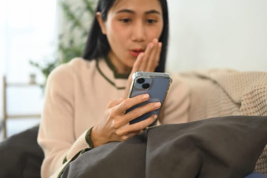 Surprised woman receiving surprising news looking at smartphone screen.