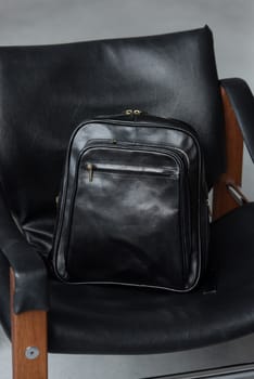 Black leather backpack on the stylish chair.