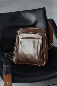 Brown leather backpack on the stylish chair.