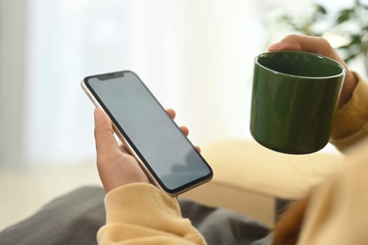 Close up person holding smartphone with white screen for app display.