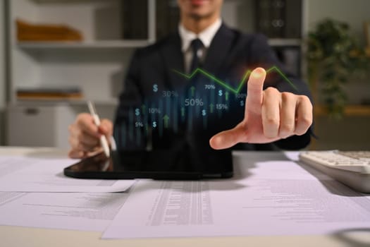 Businessman tracking and analyzing stock market performance with digital interface.