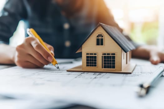 A person is drawing a house with a yellow pen. The house is small and wooden. The person is focused on the drawing, and the mood of the image is calm and peaceful