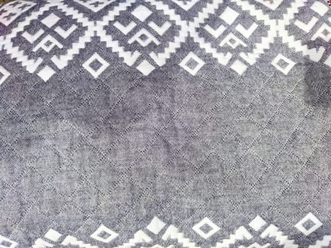 A close-up view of textured fabric displaying intricate geometric patterns in shades of gray, ideal for stylish interior designs.
