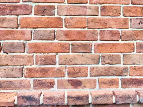 A sturdy brick wall displaying varying shades of red and distinct mortar lines under bright lighting.
