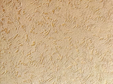 A textured beige wall surface displays a unique pattern with subtle variations in light and shadow, ideal for backgrounds.