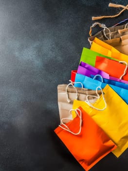 Assortment of vibrant shopping bags against a dark background, showcasing retail diversity and consumer choice, with ample copy space.