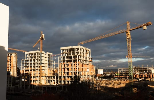 Construction boom in western Ukraine. Several cranes work on multi-story buildings on a large construction site.