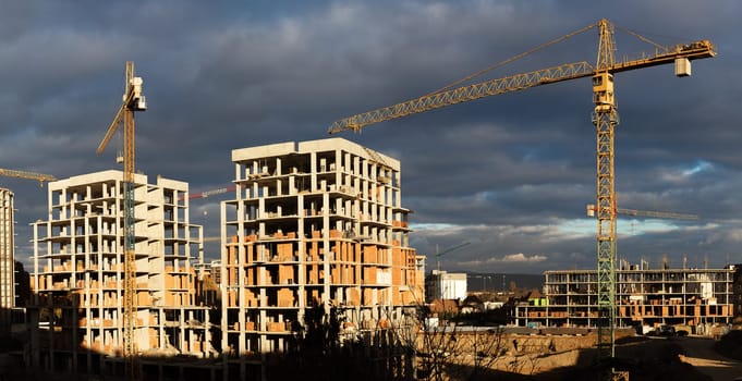 Construction boom in western Ukraine. Several cranes work on multi-story buildings on a large construction site.