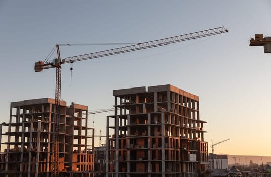 Construction boom in western Ukraine. A construction crane silhouetted against the warm glow of an early morning sky.