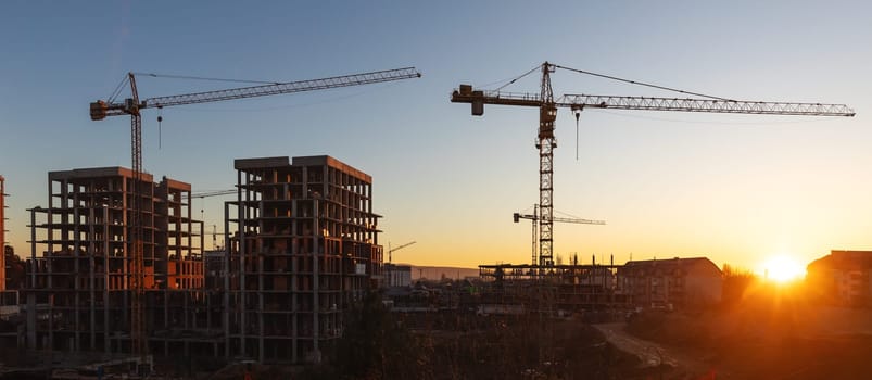 Construction boom in western Ukraine. A construction crane silhouetted against the warm glow of an early morning sky.