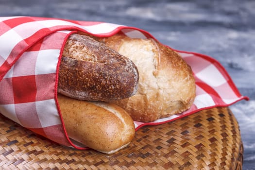 A close up of french bread and baguette wrapped up in a napkin.