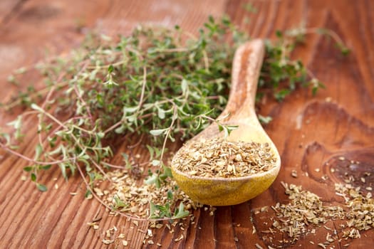 Display of dried thyme leaves on a spoon surrounded by fresh thyme leaves.