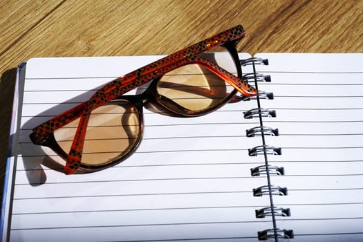 School notebook with glasses on wooden table study work education notes office business goals 2025. High quality photo